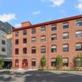 The Artemis Arlington. An old brick factory building attaches to a new modern building with beautiful landscaping in front.