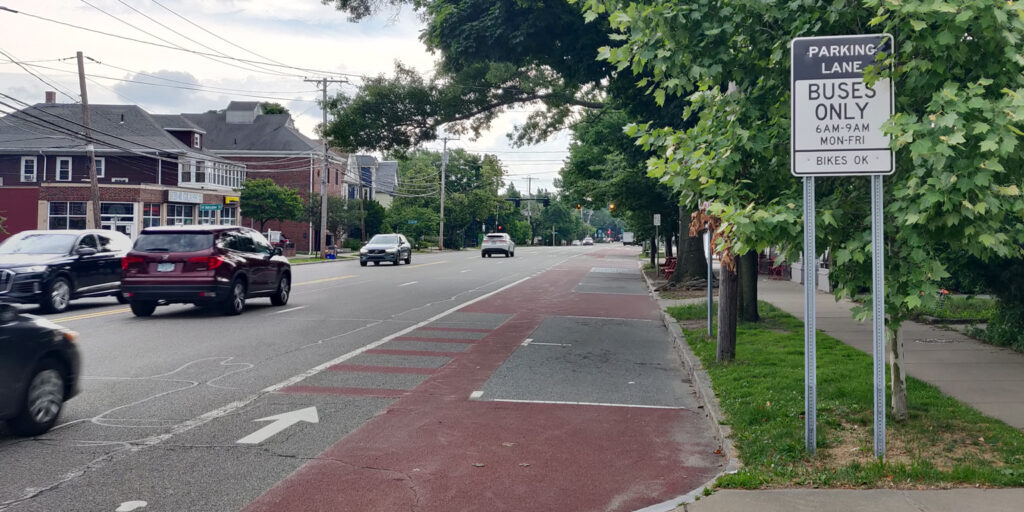 A bus priority lane.  It's a wide roadway lane marked with red paint.  Next to the lane is a sign that says "Parking lane - Buses Only 6am-9pm Mon-Fri. Bikes OK"